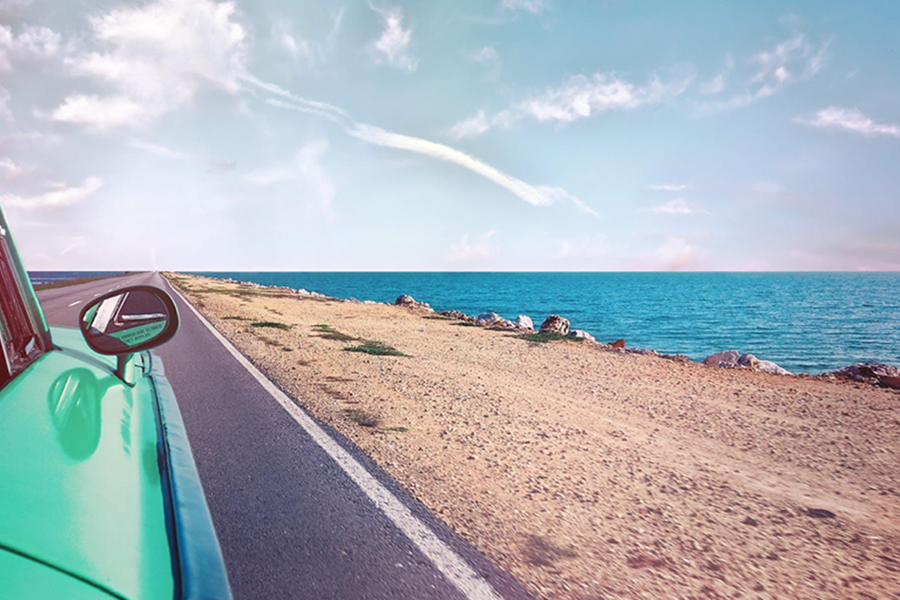 Vehicle travelling down a sunny beach road 900x600