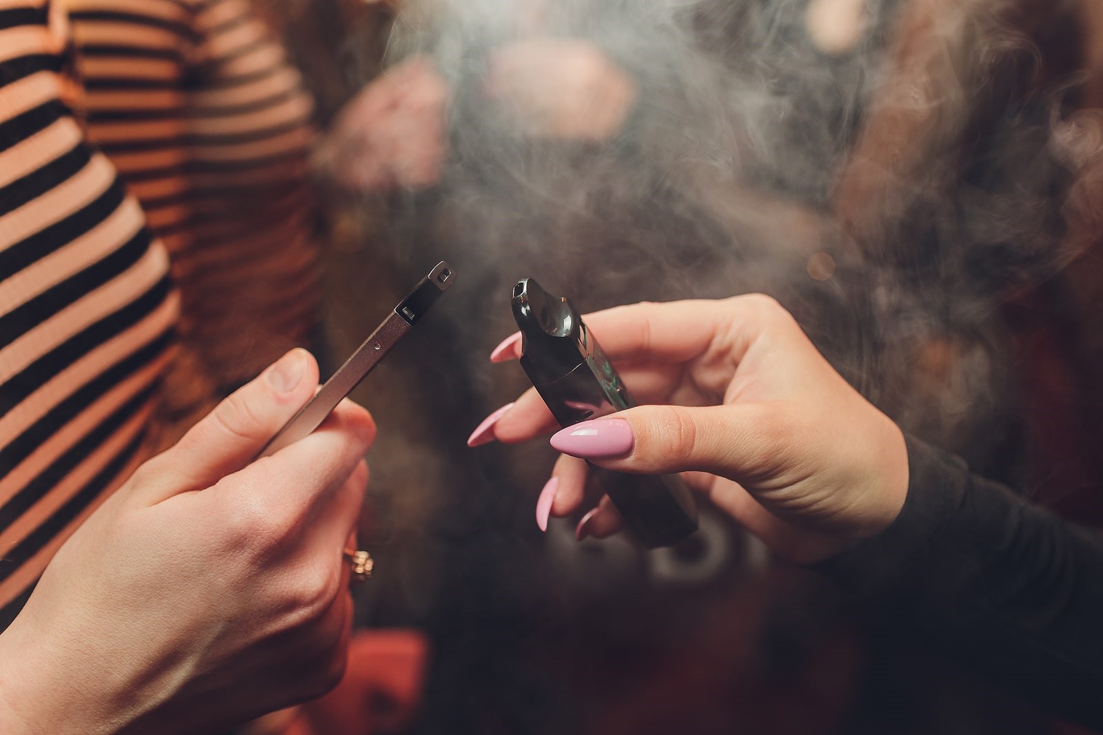 Hands holding prefilled and refillable pod vapes