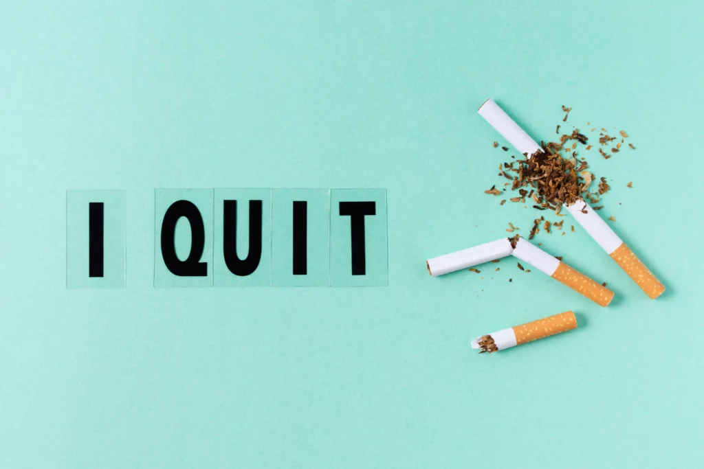 "I quit" text with broken cigarettes on a teal background.