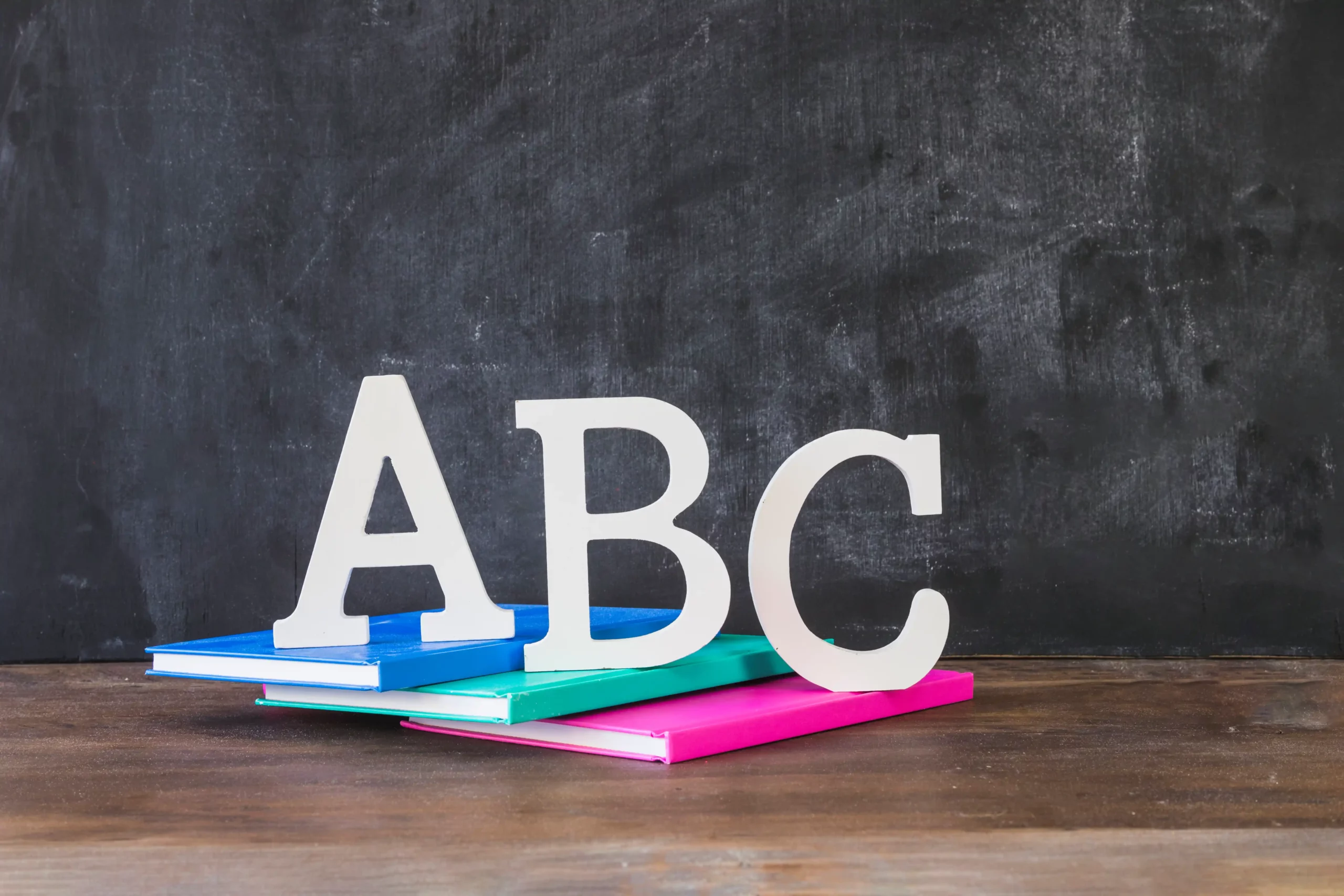 desktop-with-abc-letters-books-near-chalkboard