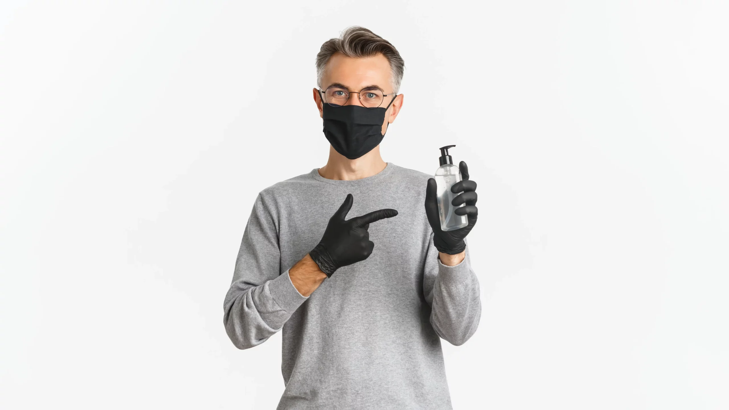 Man in mask and gloves holding hand sanitizer bottle.