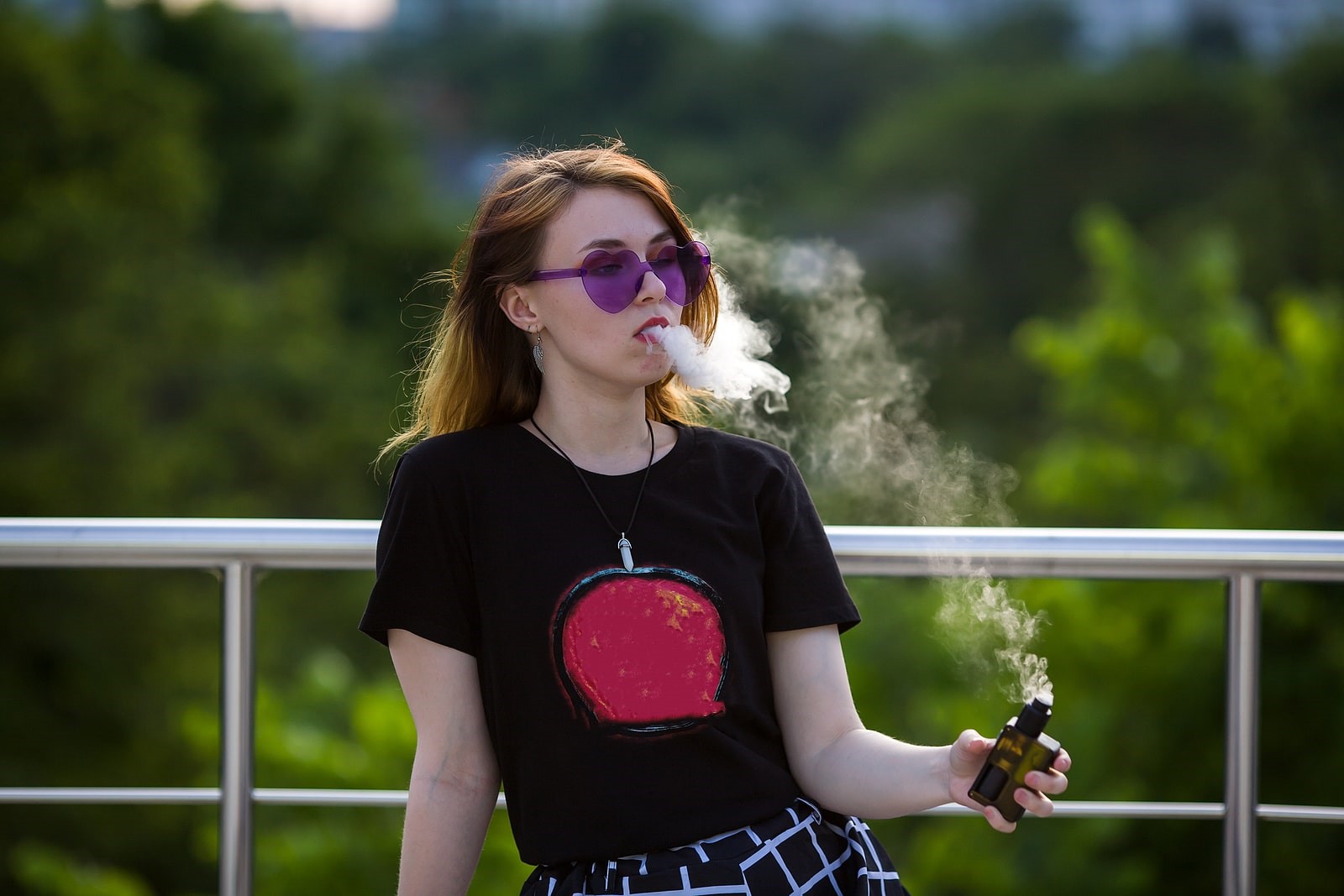 Woman vaping menthol vape juice in summer