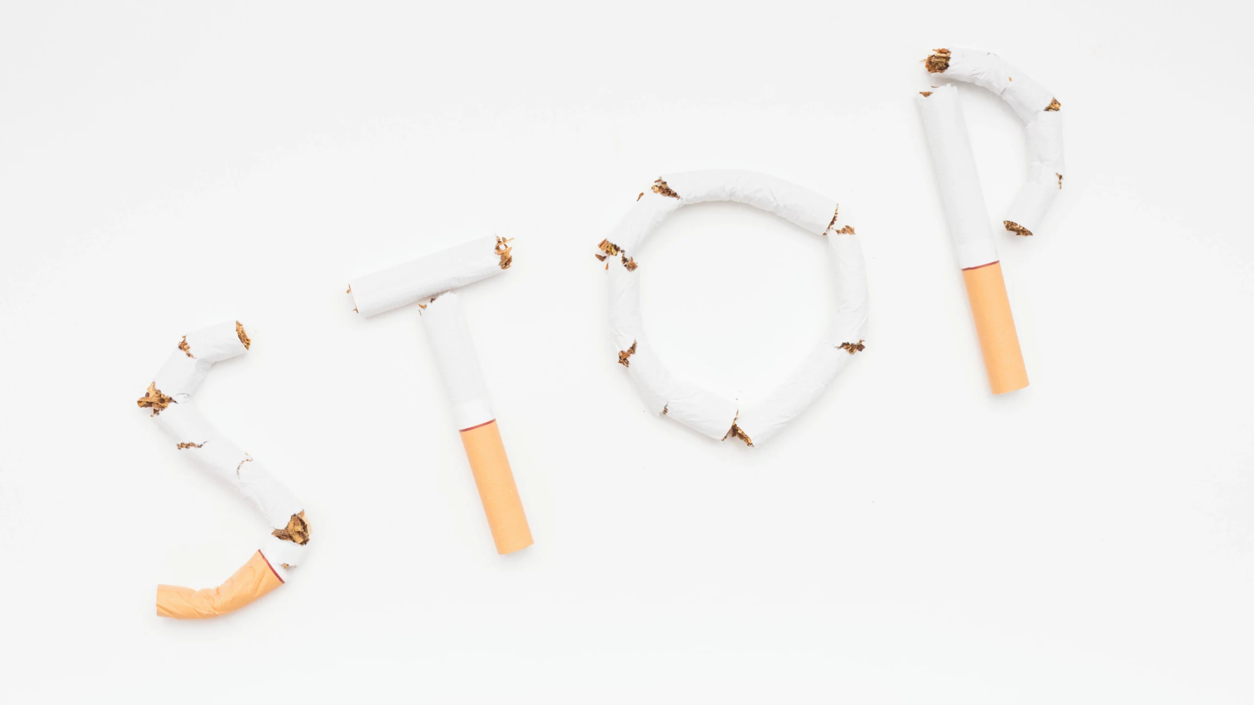 Cigarettes arranged to spell "STOP" on a white background.