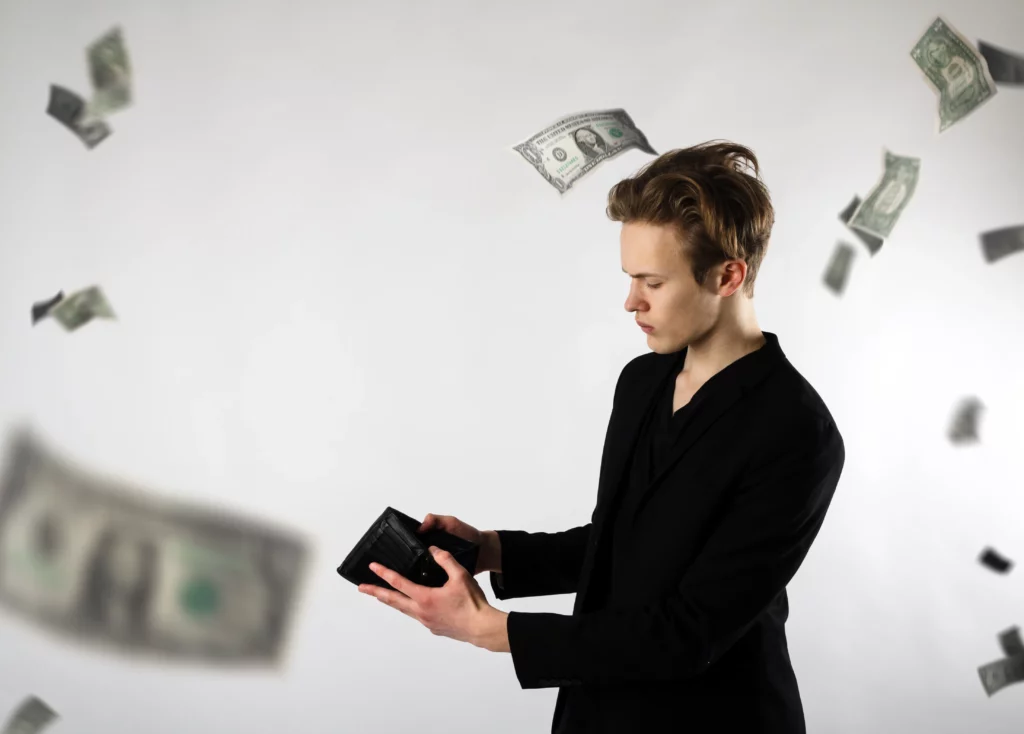 Person in black suit holding wallet, surrounded by falling dollar bills.